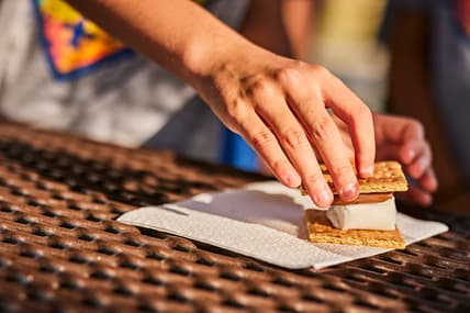 A hand assembling smores